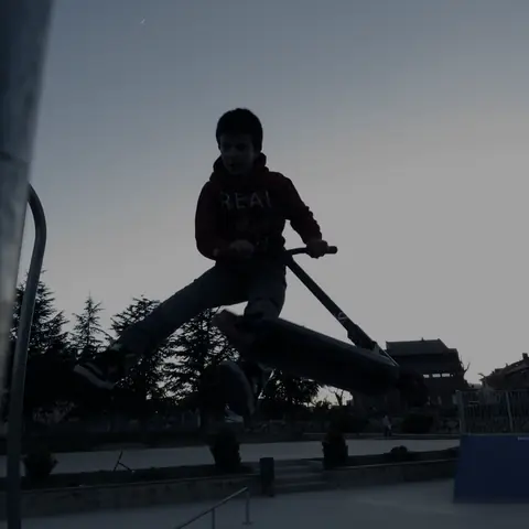 Eric, de niño, saltando con un patinete en un skatepark