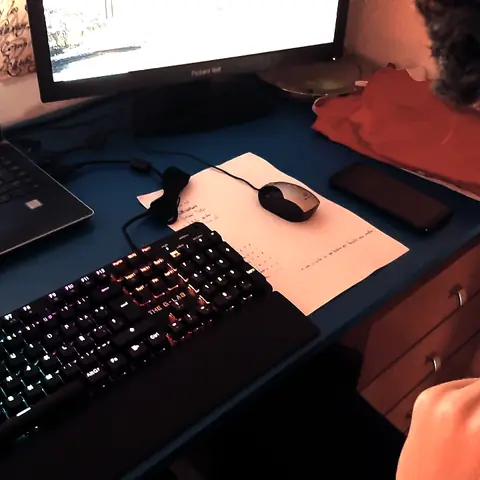 Escritorio con un portátil, un teclado retroiluminado y un monitor, en una habitación