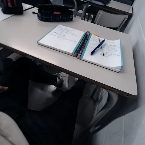Vista desde un pupitre de la última fila: un cuaderno abierto sobre la mesa